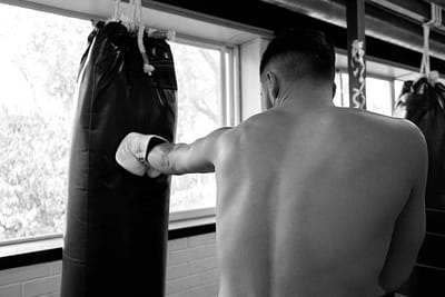 A boxer facing a heavy bag in an empty gym