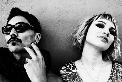 Two people leaning side by side against a wall
