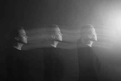 A profile repeated three times in trails of light against the dark